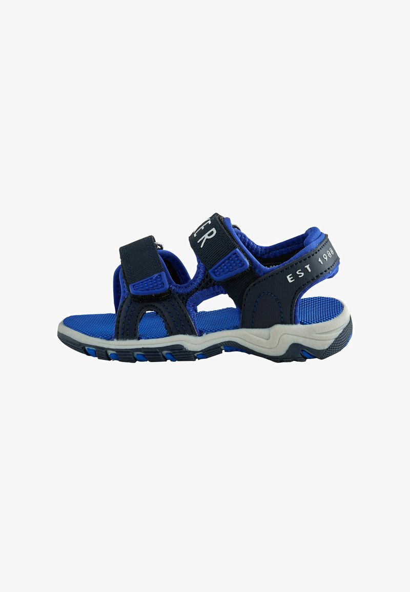 Blaue und schwarze Kindersandale mit offener Zehenpartie, verstellbaren Klettverschlüssen und profillierter Sohle, mit der Aufschrift "EST 1980" am Fersenriemen.
