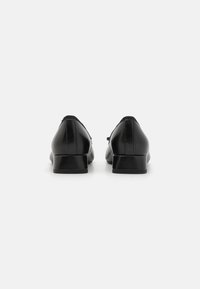 Chaussures en cuir noir avec un petit talon carré, extérieur lisse, bout arrondi et coutures minimales, vues de l'arrière.