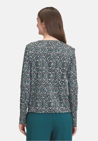 Langärmliges Hemd im Rautenmuster in Schwarz, Weiß und Petrol, mit einem runden Halsausschnitt und glatter Stofftextur.