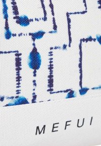 Borsa in tela con sfondo bianco che presenta un motivo geometrico blu. Include forme rettangolari blu e blu scuro con dettagli testurizzati.