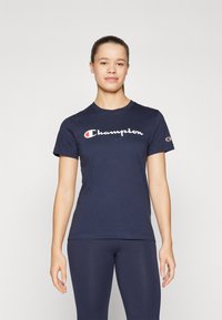 Námornícky bavlnený tričko s bielym logom "Champion" na hrudi a malým logom na ľavom rukáve. Krátke rukávy a okrúhly výstrih.