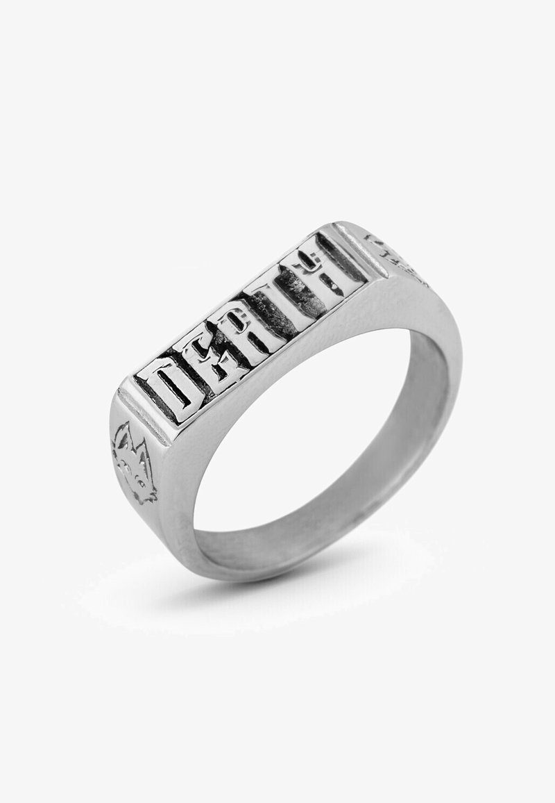 Silberner Ring mit flachem, rechteckigem Kopf, der erhabene Buchstaben zeigt. Eine Seite enthält ein stilisiertes Tiergesicht. Glatte Innenschiene.