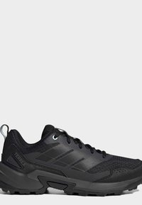 Black outdoor trail running shoe with mesh and synthetic upper, rugged sole, and pull tab at heel, shown from side on plain background.