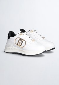 Sneaker bianche in pelle con dettagli neri, logo dorato, motivi testurizzati e la scritta "MADE TO FEEL AMAZING" incisa sulla suola. Suola in gomma.