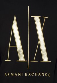 Felpa nera con logo "A/X" ricamato in oro e testo "ARMANI EXCHANGE". Texture liscia, font moderno, dettagli prominenti del logo.