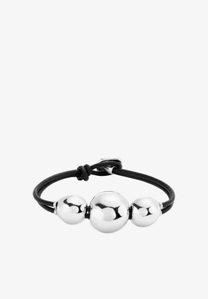 Pulsera de cuero negro con tres cuentas de metal plateado brillante de tamaños variados, aseguradas con un nudo y un cierre de metal.