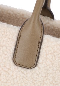 Borsa in lana beige con texture, dotata di spallacci in pelle beige liscia con cuciture visibili e un esterno morbido e peloso.