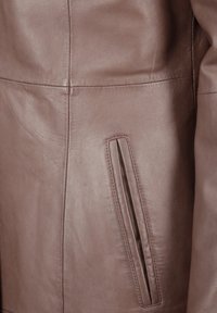 Bruine leren jas met een gladde textuur, zijnaad en een discreet vak met een horizontale gleufdetail.