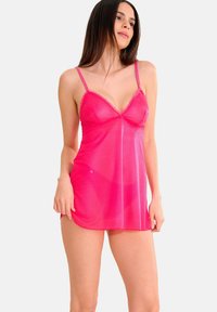 Nuisette rose en chiffon avec des bretelles fines et un décolleté en V, en tissu texturé et avec un éclat subtil, tombant jusqu'à mi-cuisse.
