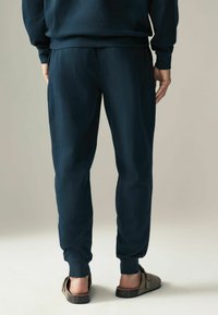 Marineblauwe fleecesweaters met elastische boorden en zijzakken, met een zachte textuur. Gestyled met casual instap schoenen.