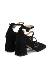 Chaussures à talons hauts en daim noir avec de larges talons carrés, bout pointu et accents décoratifs en faux bijoux noirs sur plusieurs brides.