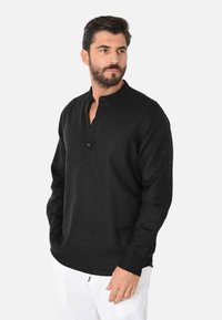 Camicione nero a maniche lunghe in lino, con colletto alla cinese, patta con bottoni e polsini con dettagli a bottone.