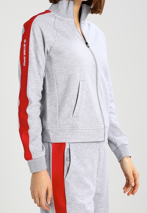 Gray zip-up sweatshirt with red side stripes, high collar, and pockets. Soft fabric, close-fitting design. Brand logo on sleeve.