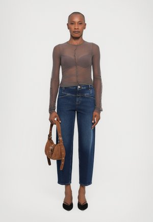 Sheer gray long-sleeve top with button detail, high-waisted blue denim jeans, and a brown suede handbag, featuring a rounded shape and strap.