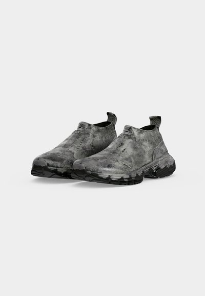 Спортни обувки ниски, тип slip-on с черно и сиво камуфлажно шарка и дебели черни подметки, показани един до друг на бял фон.