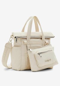 Beige tote bag with a zippered top, dual handles, and a detachable front pouch. Fabric is smooth with structured sides and silver hardware accents.
