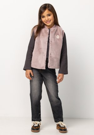 Hellblau-lila Kunstpelzweste mit Druckknöpfen über einem dunklen Langarmshirt, kombiniert mit dunklen Jeans und Sneakers im Tiermotiv.