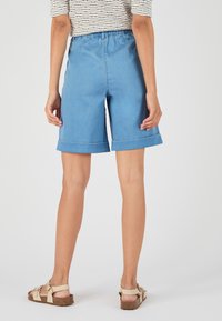 Shorts de mezclilla azul claro con cinturilla elástica, puños doblados, textura suave y detalle de costura en contraste. No hay bolsillos visibles.