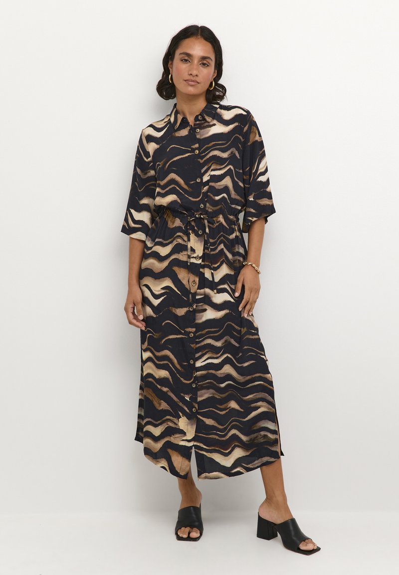 Vestido abotonado en azul oscuro con patrones ondulados en beige y marrón, ceñido a la cintura con un lazo. Mangas cortas y longitud midi.