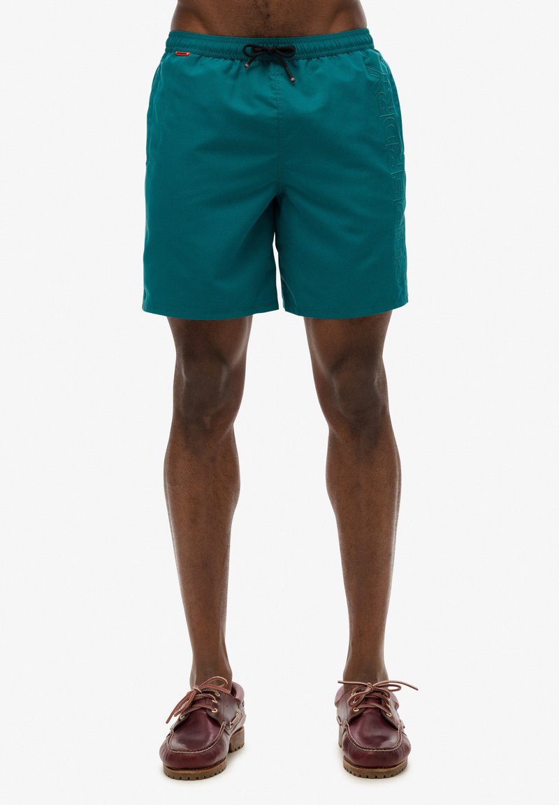 Teal zwemshorts met een verstelbare tailleband, zijzakken en een gestructureerd logo op het linkerpootje. Glad, lichtgewicht materiaal.