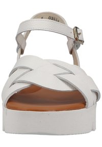Białe skórzane sandały na platformie z krzyżującymi się paskami, z zapięciem na kostce i gładką brązową podeszwą. Regulowany pasek dla lepszego dopasowania.