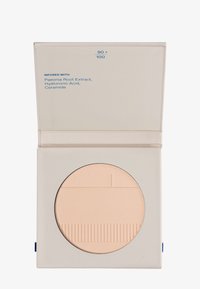 Kompakter beige Kosmetikpuder in einem quadratischen hellbeigen Etui, etikettiert mit den Inhaltsstoffen Pfingstrosenwurzelextrakt, Hyaluronsäure und Ceramid.