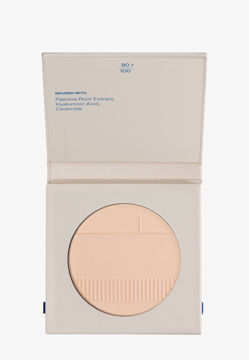 Kompakter beige Kosmetikpuder in einem quadratischen hellbeigen Etui, etikettiert mit den Inhaltsstoffen Pfingstrosenwurzelextrakt, Hyaluronsäure und Ceramid.
