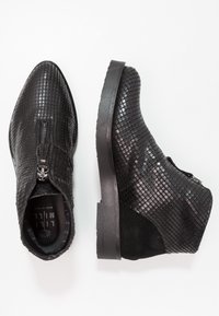 Botas negras hasta el tobillo con un patrón texturizado similar a un reptil, cierre de cremallera y suela de goma negra sólida. Cuero suave en la parte frontal; acentos de ante.