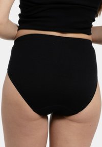 Hochgeschnittene schwarze Baumwollunterwäsche mit einer glatten Textur, ausgestattet mit einem elastischen Bund und nahtlosen Kanten für Komfort und Bedeckung.