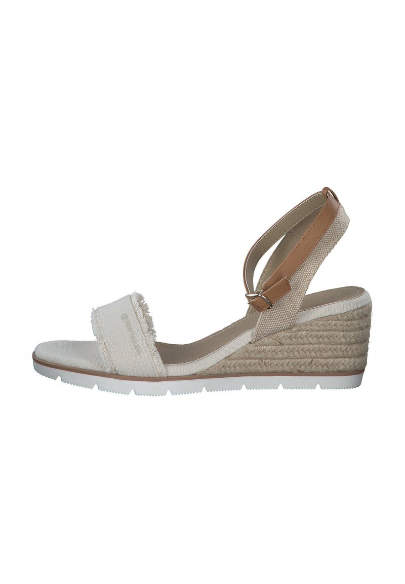 Sandale compensée avec une tige en tissu beige, détail de franges sur la sangle et un talon en jute texturé. Sangle de cheville ajustable pour un bon maintien.