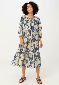 Kleid mit floralem Muster, langärmlig in Marineblau und Creme, mit gelben Akzenten. Verfügt über einen Schlüssel-Ausschnitt und einen gestuften Saum, aus leichtem Stoff gefertigt.