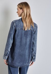 Camicia in denim di un blu sbiadito, con maniche lunghe e polsini con button. Tessuto morbido con una vestibilità comoda e un orlo curvo sul retro.