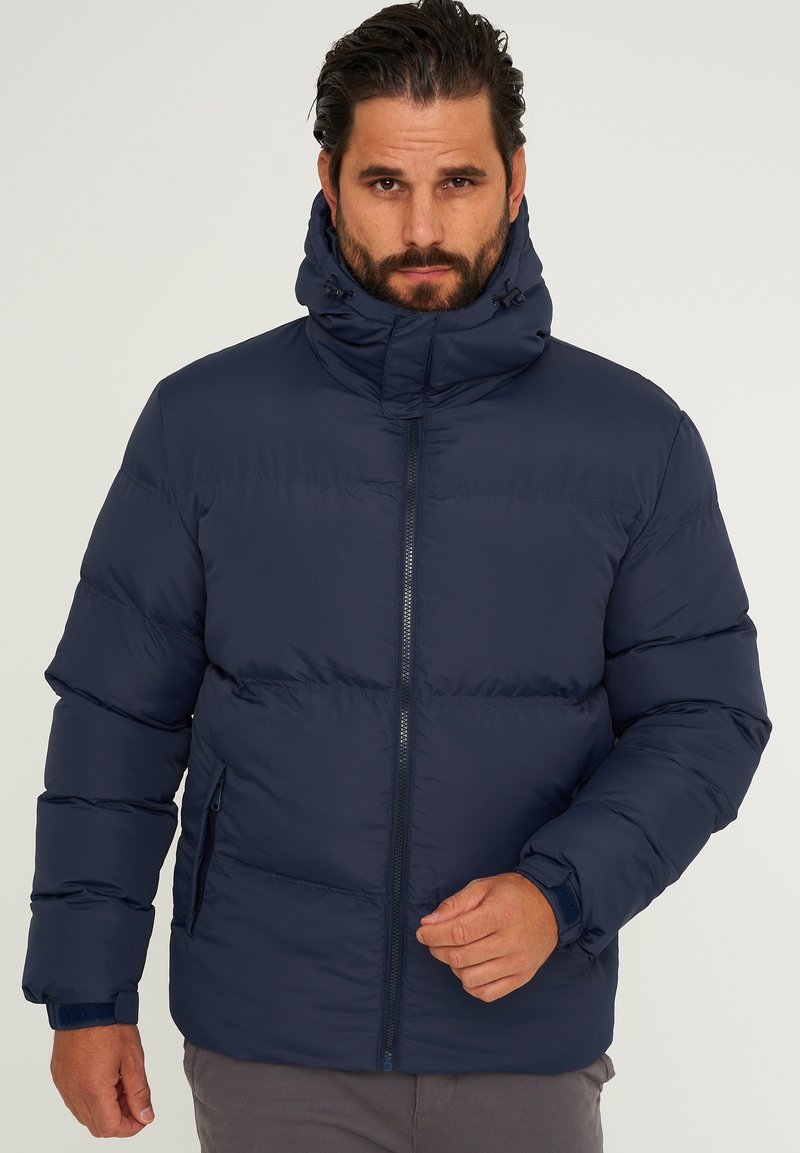 Marineblaue Steppjacke mit hohem Kragen, Reißverschluss vorne und elastischen Bündchen. Verfügt über ein schlankes Design mit gesteppter Struktur für Wärme.