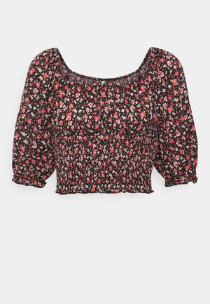 Top corto floreale nero con maniche a sbuffo corte, corpetto smock e scollatura quadrata, decorato con un motivo di piccoli fiori rossi e bianchi.