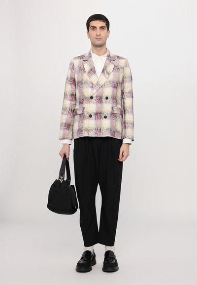 Blazer croisé aux couleurs pastel, avec de larges revers et des boutons noirs, associé à un pantalon noir ample et un petit sac noir.
