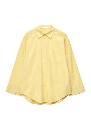 Keltainen pitkähihainen nappipaita, jossa ohuet pystysuorat raidat, terävä kaulus, rintatasku ja pyöristetty helma.