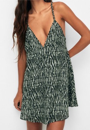 Robe verte avec un profond décolleté en V et fines bretelles, présentant un motif imprimé animal texturé dans des nuances plus claires de vert et de crème.