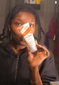 Curlsmith Ruby Hair Makeup tube, 30 oz, heeft een transparant lichaam met een witte flip-cap en oranje merkdetails.