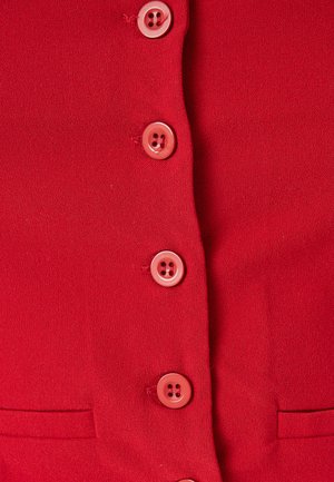 Top de tela roja con un diseño de botones en la parte delantera que cuenta con seis botones rosas, superficie texturizada y un pequeño detalle de bolsillo en el lado izquierdo.