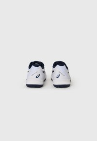 Baskets de sport blanches avec un dessus en textile lisse, des accents marins, un dos texturé et une semelle extérieure en caoutchouc noir. Présente un logo sur le talon.