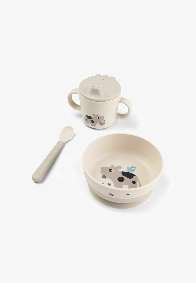 Set de mese pentru copii format din trei piese, care include un bol bej, o cană cu design de vacă și o linguriță asortată, realizate dintr-un material moale și durabil.