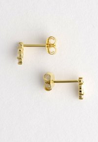 Un paio di piccoli orecchini a bottone in oro con gemme tonda e trasparente, mostrati di lato e sul retro su uno sfondo bianco.