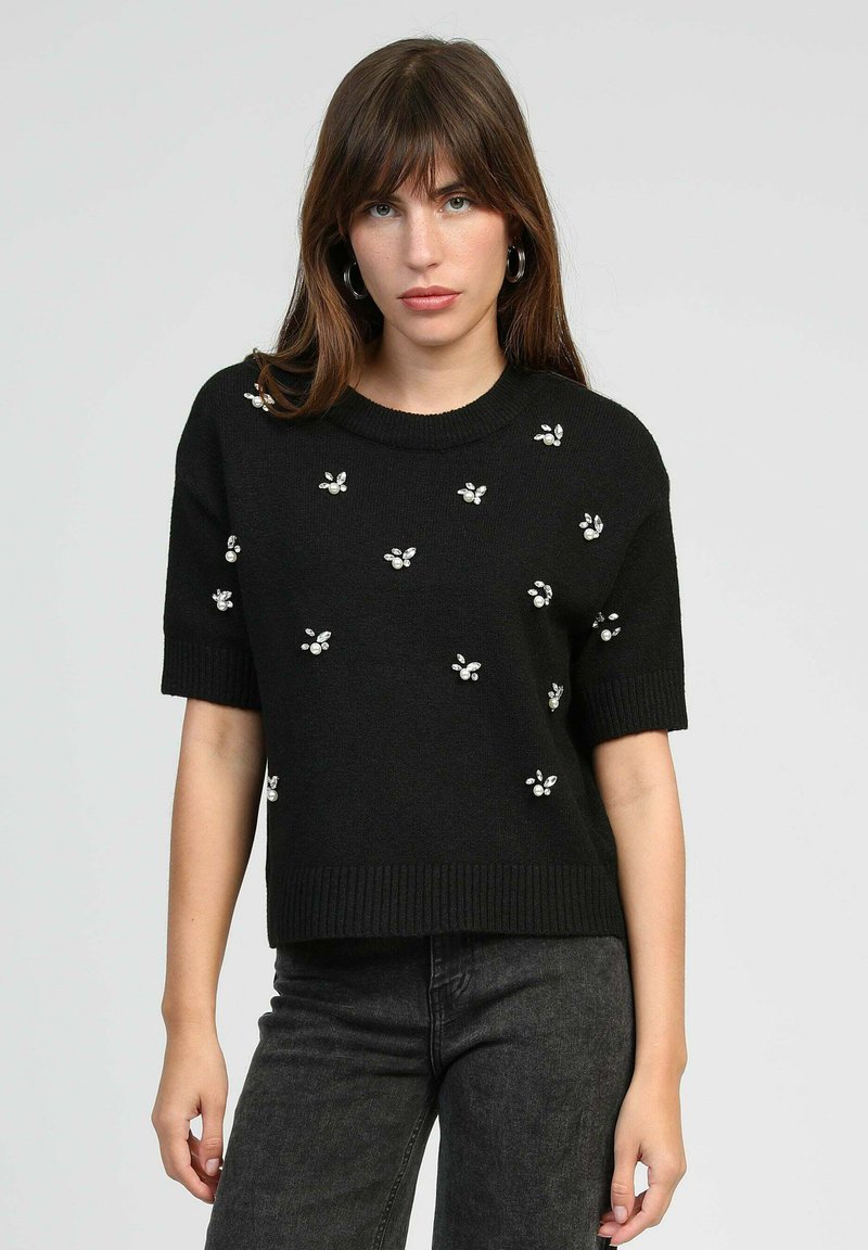 Pull noir à manches courtes avec ourlet côtelé, orné de motifs floraux en petites perles sur le devant.