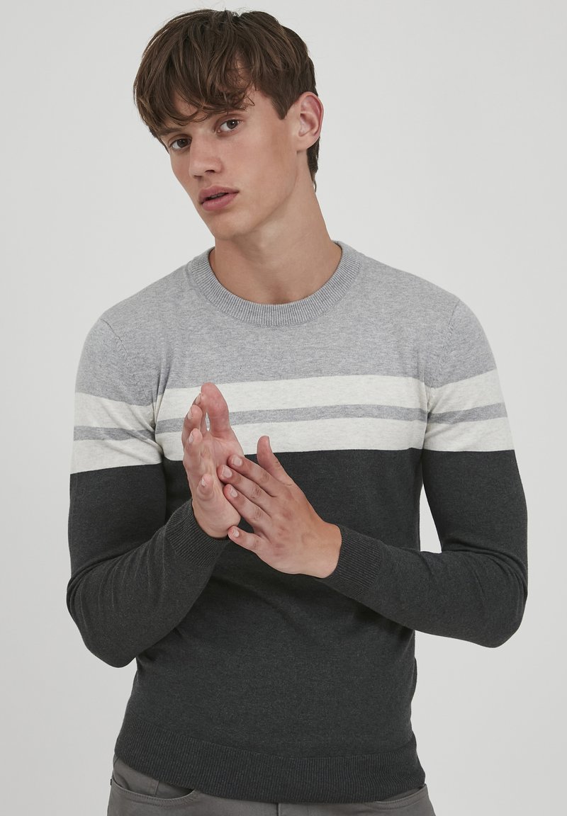 Grijze en zwarte gebreide trui met horizontale strepen in lichtgrijs en crème. Classic crew neck, ribgebreide boorden en zoom.