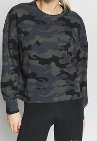 Sweatshirt camouflage dans des tons de vert et de noir, avec un col ras du cou, des manches longues et une coupe décontractée avec des poignets et un ourlet côtelés.