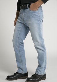 Helle blaue Jeans mit geradem Bein, subtiler Waschung und Seitentaschen, kombiniert mit schwarzen Lederschuhen.