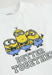 White cotton t-shirt featuring three yellow Minion characters in blue overalls. Text below reads "BETTER TOGETHER" in bold black letters.