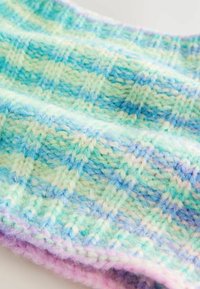 Écharpe tricotée dans des teintes pastel de vert menthe, bleu doux et lavande. Présente un motif en damier texturé avec une finition duveteuse.