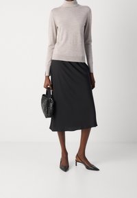 Jasnoszary golf, czarna satynowa spódnica na ramiączkach, czarna pleciona torebka i czarne czółenka z ostrym noskiem. Prosty i elegancki design.