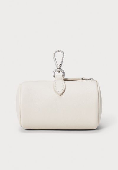 Kremo spalvos odinė maišelis cilindro formos, sidabrinė metalinė įranga ir viršuje kilpa prisegimui. Lygi tekstūra, minimalistinis dizainas.